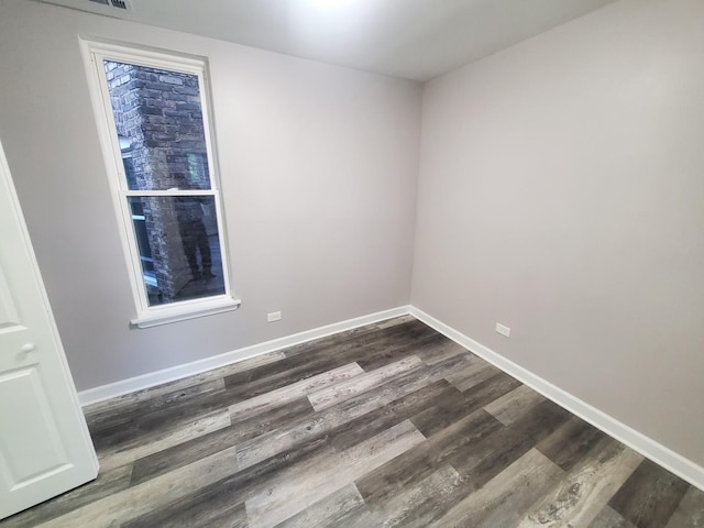 empty room with baseboards and dark wood-type flooring