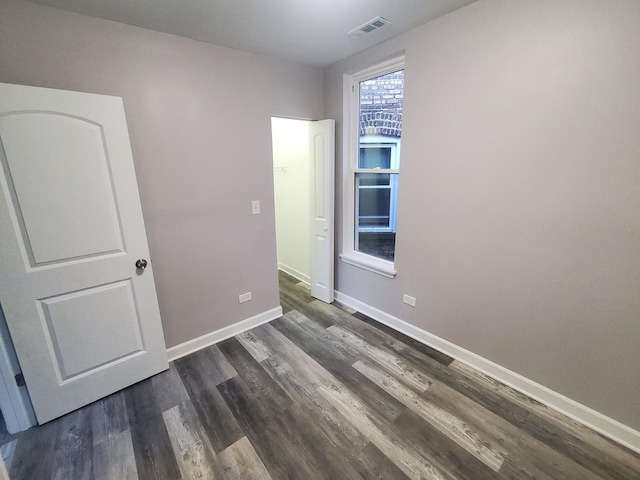 unfurnished bedroom featuring visible vents, baseboards, and dark wood-style floors