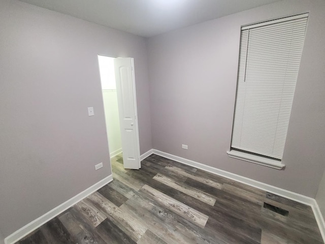 spare room with baseboards and dark wood-style flooring