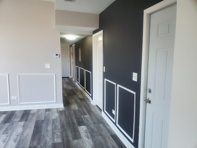 corridor with visible vents, baseboards, and dark wood-style flooring