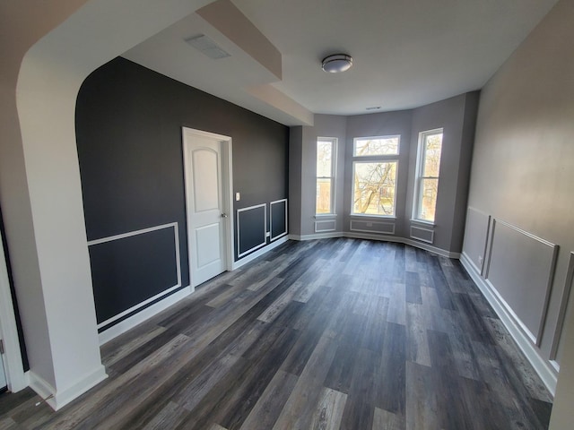 spare room featuring dark wood-style floors, visible vents, and baseboards