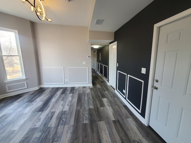 interior space with visible vents, baseboards, dark wood-type flooring, and an inviting chandelier