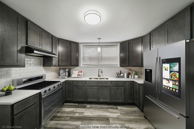 kitchen with under cabinet range hood, a sink, tasteful backsplash, appliances with stainless steel finishes, and light countertops