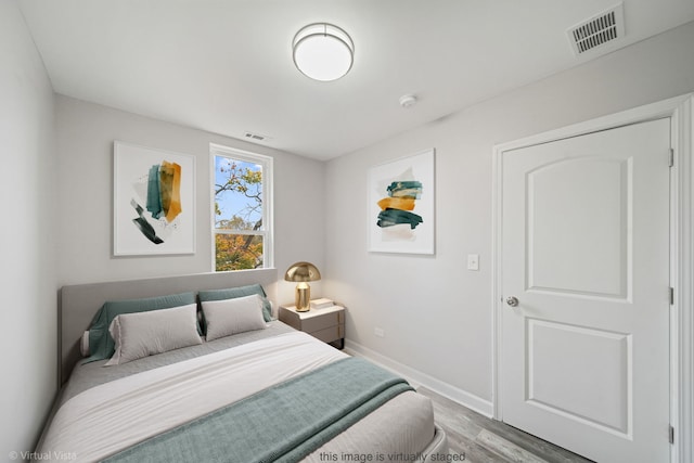 bedroom with visible vents, baseboards, and wood finished floors