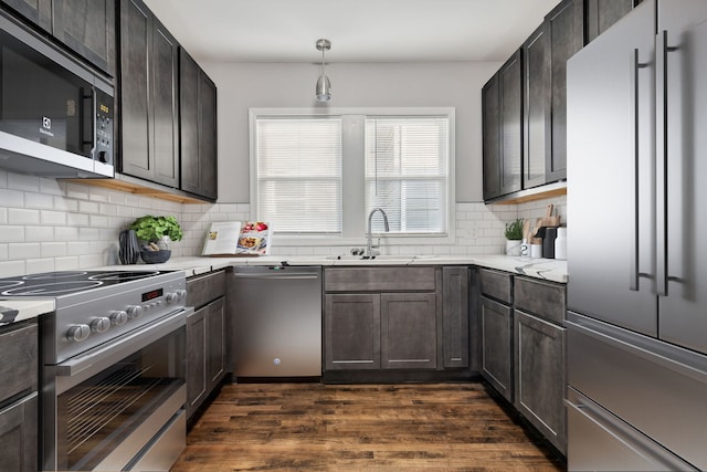 kitchen featuring dark hardwood / wood-style flooring, tasteful backsplash, sink, pendant lighting, and high quality appliances