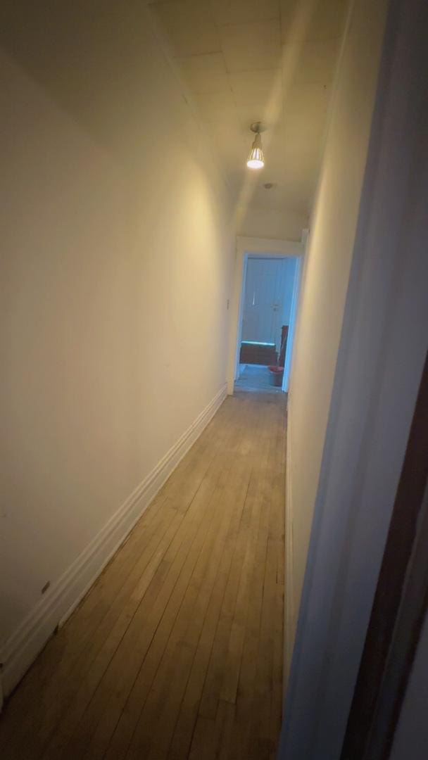 corridor featuring hardwood / wood-style flooring and baseboards