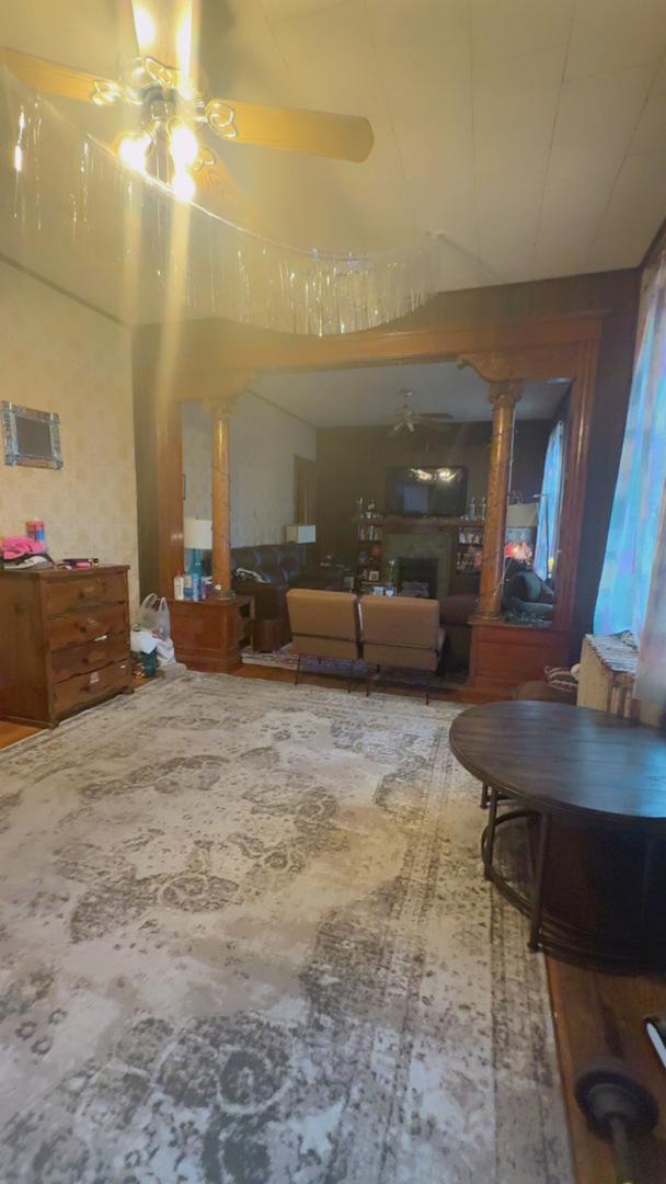 living room featuring a ceiling fan, decorative columns, and a fireplace