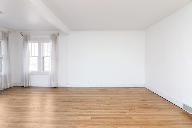 empty room featuring light hardwood / wood-style flooring and beam ceiling