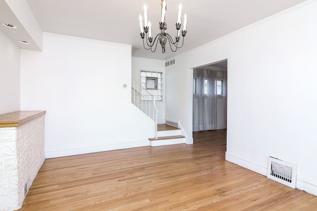 unfurnished dining area with light hardwood / wood-style floors, ornamental molding, and a chandelier