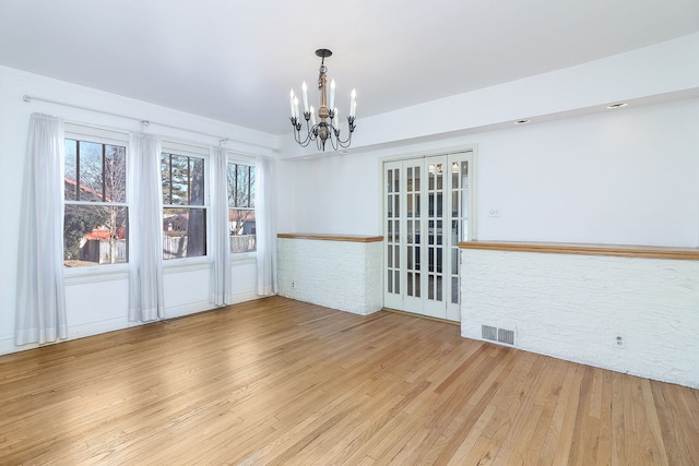 unfurnished dining area with light wood-type flooring and a notable chandelier