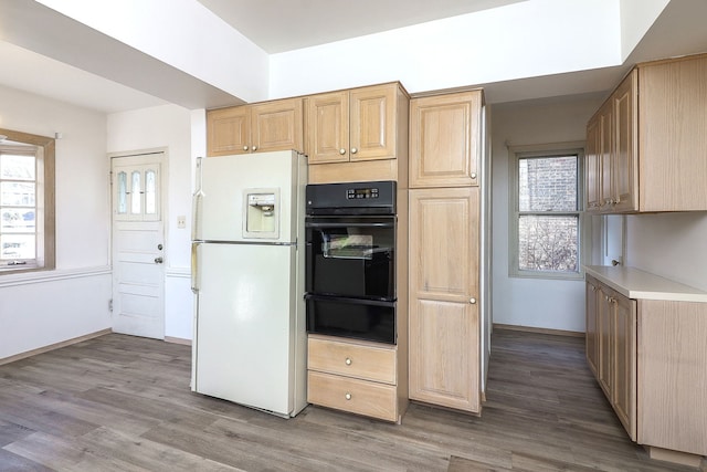 kitchen featuring wood-type flooring, light brown cabinetry, and white refrigerator with ice dispenser