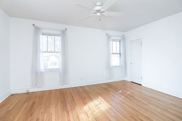 empty room featuring ceiling fan, a healthy amount of sunlight, and light wood-type flooring