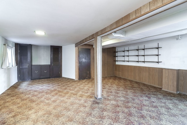 basement featuring light colored carpet and wood walls