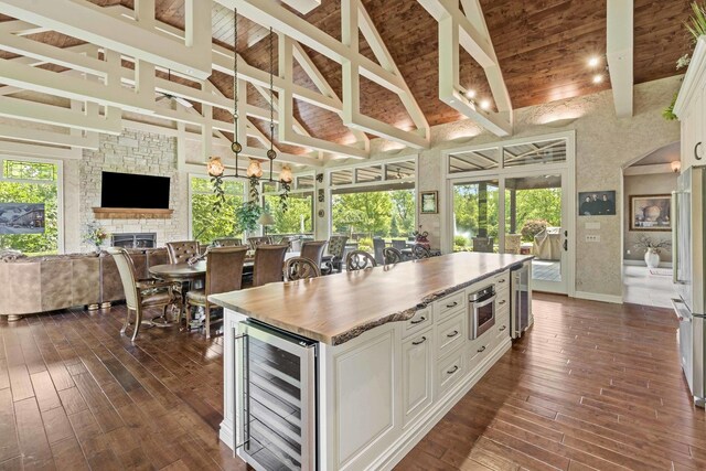 kitchen with a center island, a fireplace, wine cooler, dark wood-type flooring, and white cabinetry