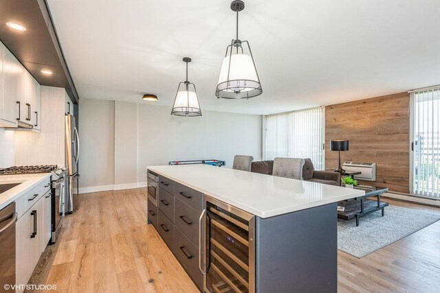 kitchen featuring hanging light fixtures, white cabinetry, light hardwood / wood-style floors, wine cooler, and appliances with stainless steel finishes