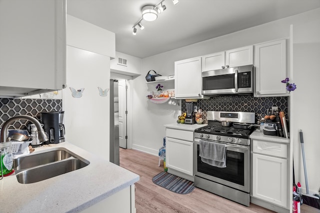 kitchen featuring sink, appliances with stainless steel finishes, tasteful backsplash, track lighting, and white cabinetry