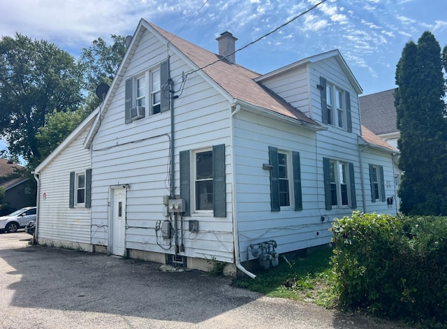 view of side of home with a shingled roof and a chimney