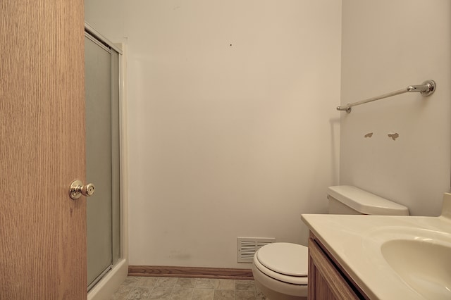 bathroom with a shower with shower door, toilet, vanity, and tile patterned floors