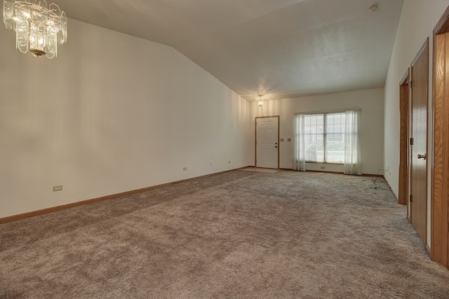 carpeted empty room featuring an inviting chandelier and lofted ceiling