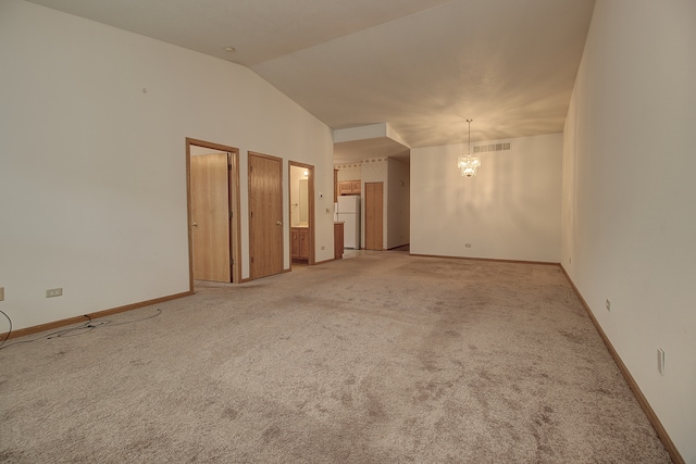 carpeted spare room with lofted ceiling and a chandelier