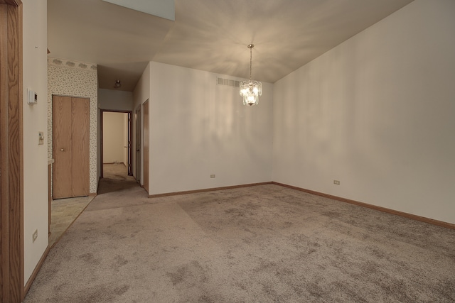 carpeted empty room featuring a notable chandelier