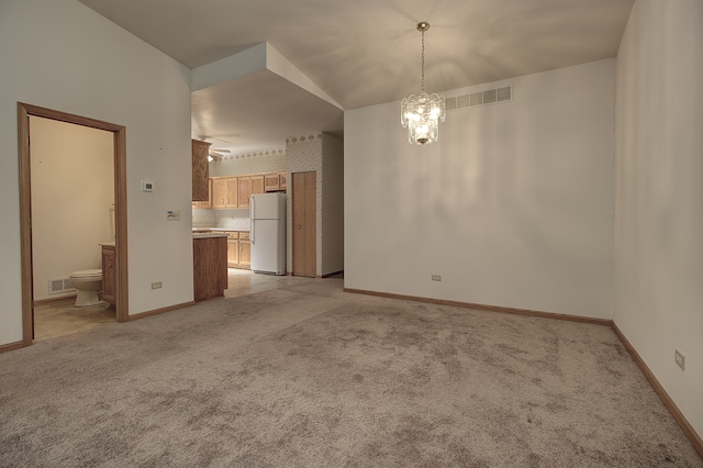 interior space with light colored carpet, vaulted ceiling, and an inviting chandelier