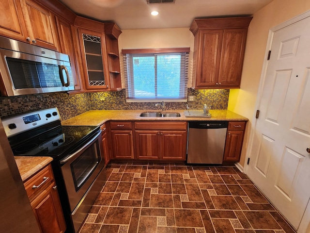 kitchen featuring stainless steel appliances, light stone counters, tasteful backsplash, and sink