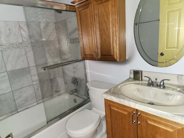 full bathroom featuring combined bath / shower with glass door, vanity, and toilet