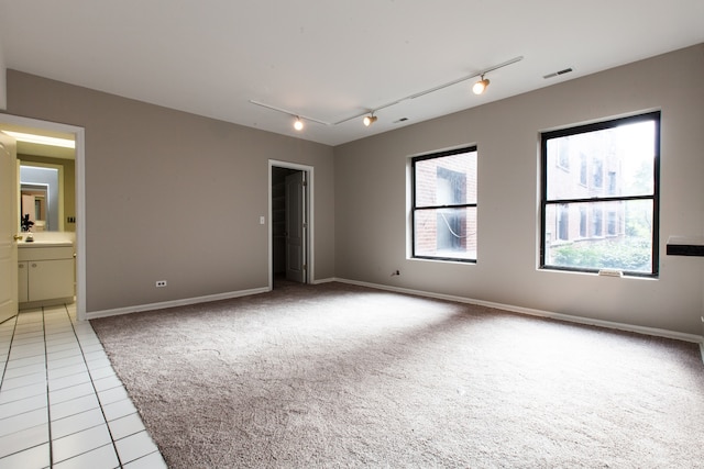 empty room with sink, light tile patterned flooring, and rail lighting