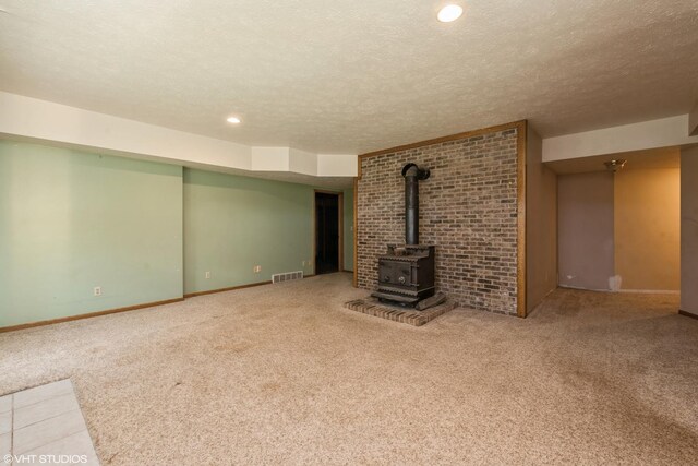 unfurnished living room featuring carpet floors, brick wall, and a wood stove