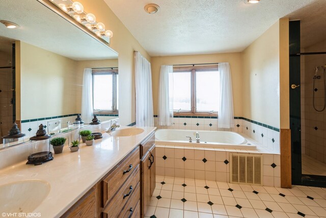 bathroom featuring shower with separate bathtub, double vanity, tile patterned flooring, and a textured ceiling