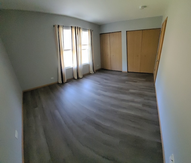 unfurnished bedroom featuring two closets and wood-type flooring