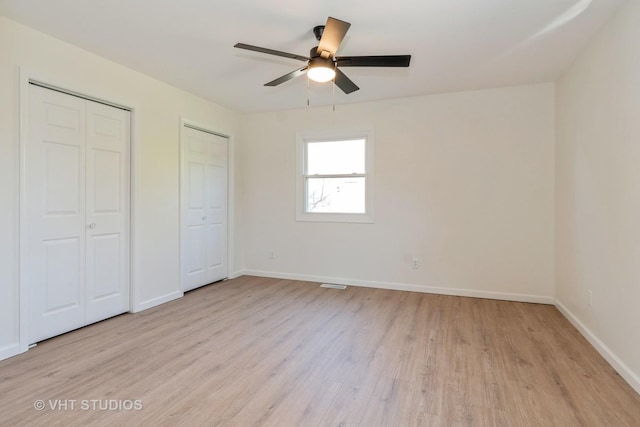 unfurnished bedroom featuring light wood-type flooring, two closets, and ceiling fan