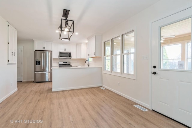 kitchen featuring white cabinetry, a healthy amount of sunlight, light wood-type flooring, and appliances with stainless steel finishes