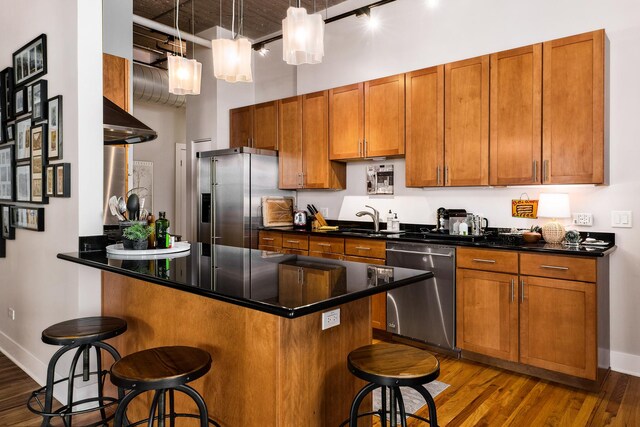 758 N Larrabee St Unit 811, Chicago, IL 60654 - kitchen featuring appliances with stainless steel finishes, a kitchen breakfast bar, brown cabinets, and wood finished floors