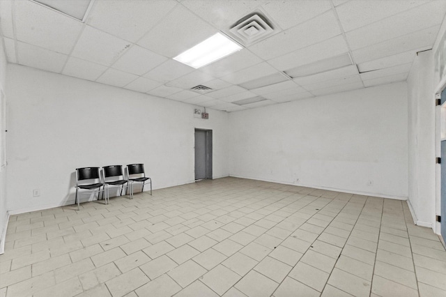 tiled empty room featuring a drop ceiling