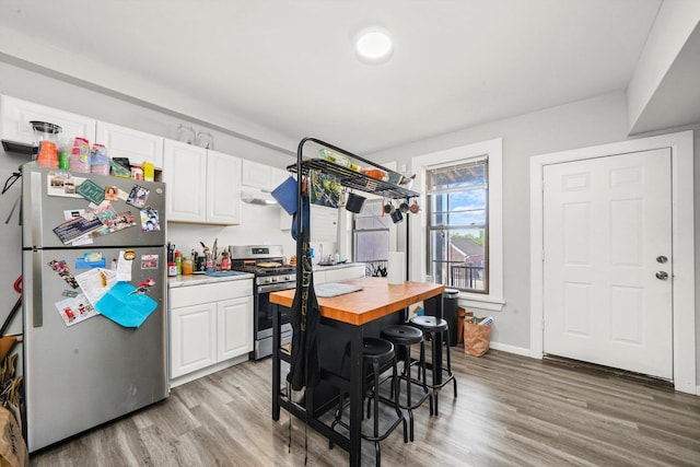 kitchen featuring butcher block countertops, white cabinets, light hardwood / wood-style floors, and appliances with stainless steel finishes