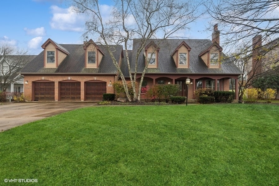 cape cod house with a front yard and a garage