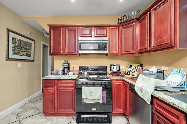 kitchen featuring light stone countertops, stainless steel appliances, and light tile patterned floors