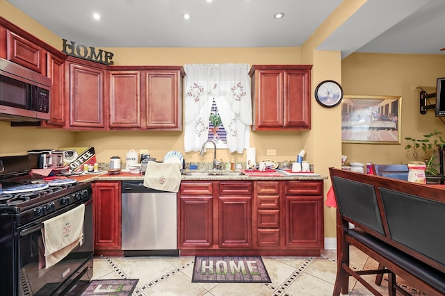 kitchen with sink, light stone counters, and stainless steel appliances