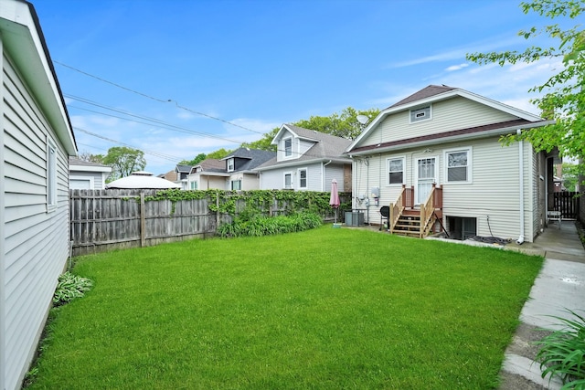 rear view of house featuring central air condition unit and a lawn