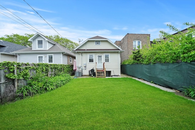 rear view of house with cooling unit and a lawn