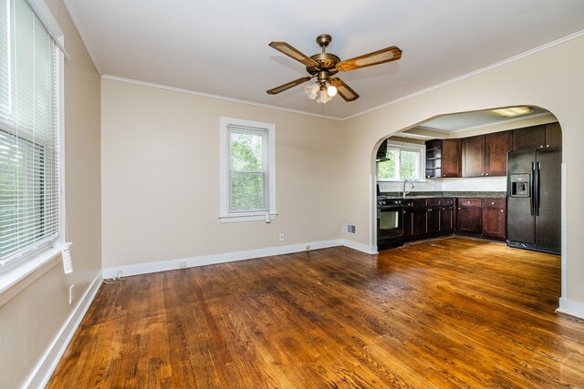 interior space featuring black refrigerator with ice dispenser, dark wood-type flooring, a healthy amount of sunlight, and dark brown cabinetry