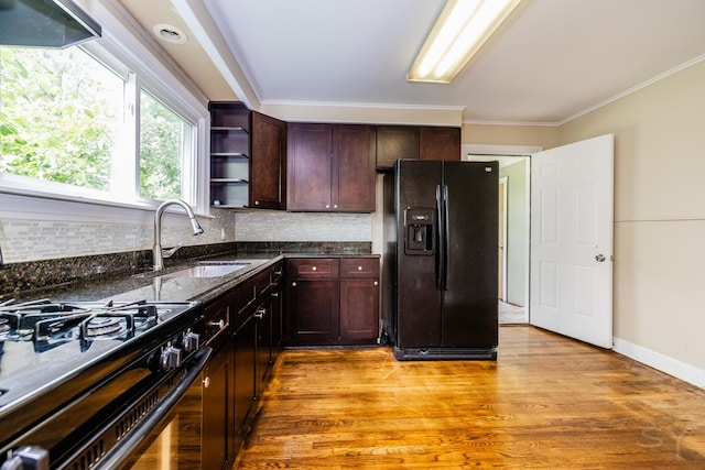 kitchen featuring light wood finished floors, decorative backsplash, black appliances, open shelves, and a sink