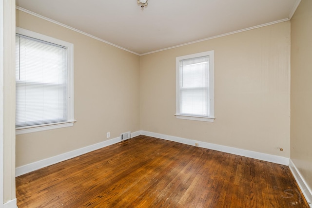 unfurnished room featuring ornamental molding, visible vents, baseboards, and wood finished floors