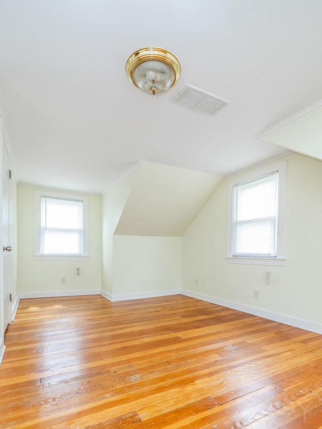 additional living space featuring light wood-style flooring, visible vents, and baseboards