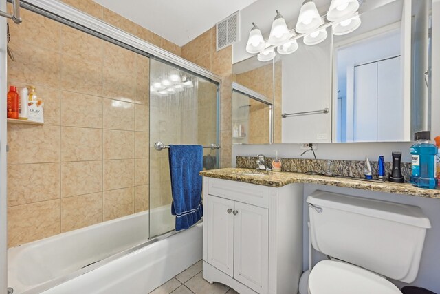 full bathroom with tile patterned flooring, vanity, bath / shower combo with glass door, and toilet