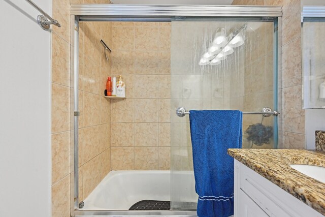 bathroom featuring shower / bath combination with glass door and vanity