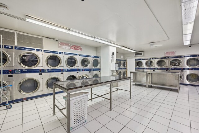 playroom with light tile patterned floors, stacked washing maching and dryer, and washing machine and clothes dryer