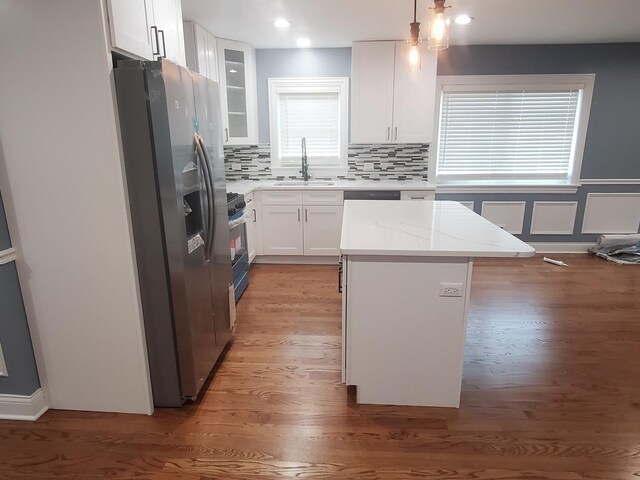 kitchen featuring appliances with stainless steel finishes, white cabinetry, light hardwood / wood-style flooring, and pendant lighting